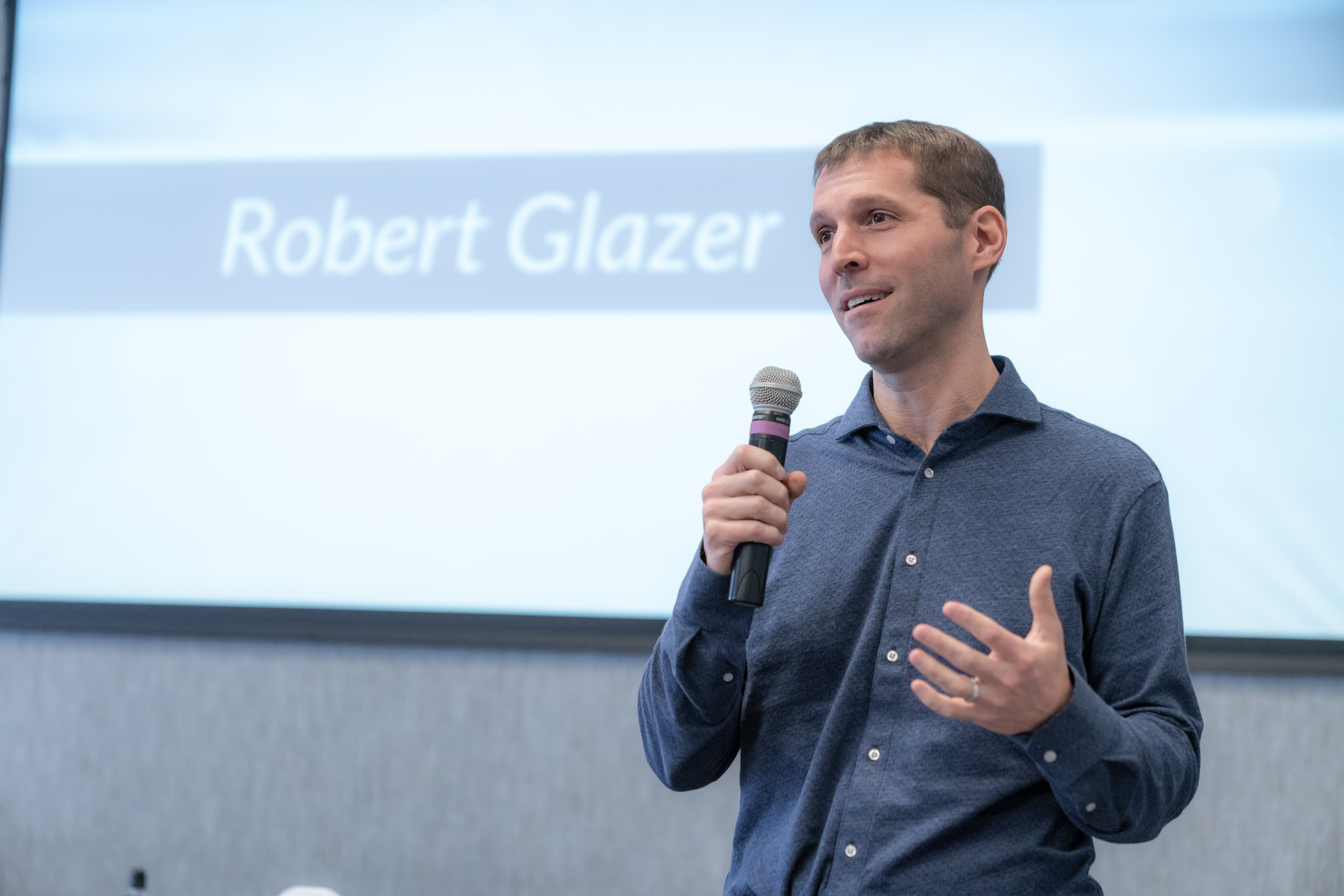Robert Glazer speaking at an event holding a microphone