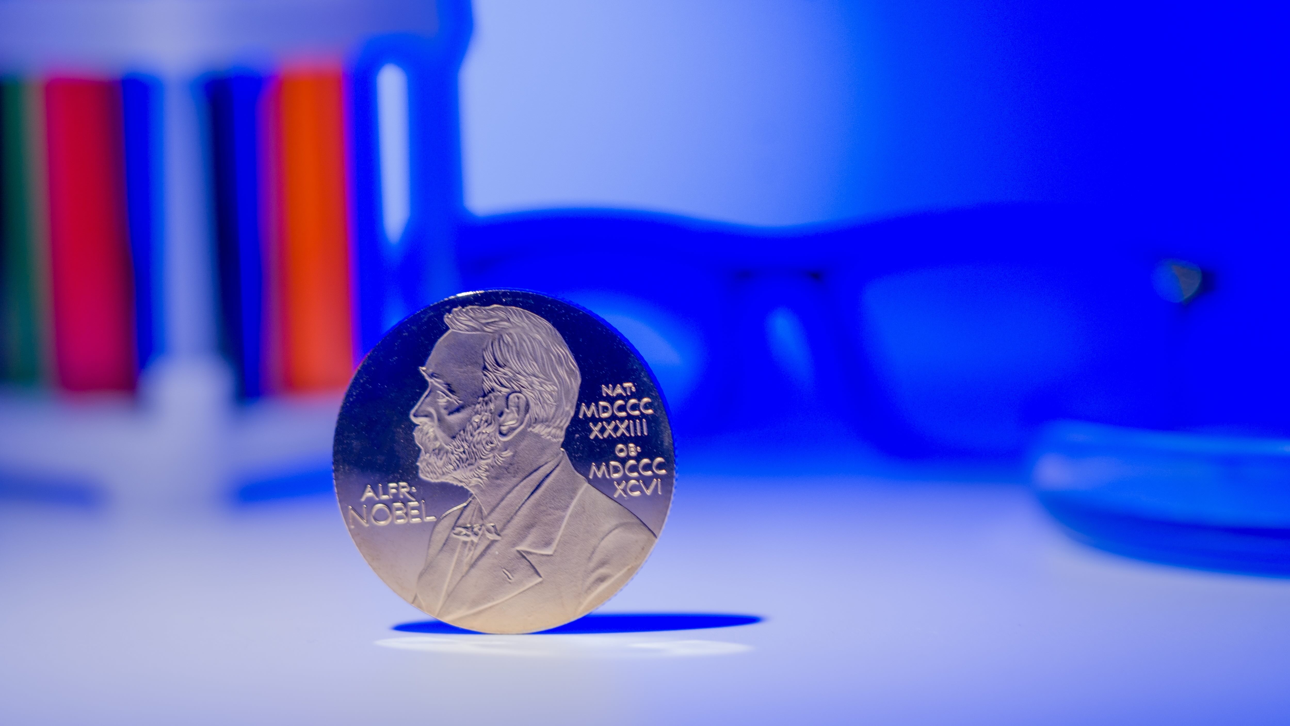 Nobel Prize medal standing upright with scientific equipment blurred in background