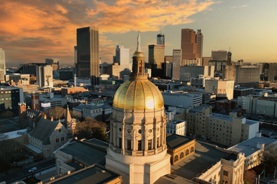 Morning sun on the gold dome of the Georgia State Capitol building with the Atlanta,  Georgia skyline in the background.