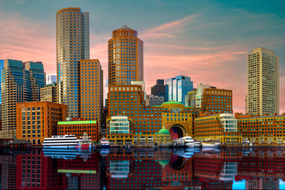 Boston Harbor and Financial District Skyline at sunset with vibrant colors of the clouds, buildings, and reflections 