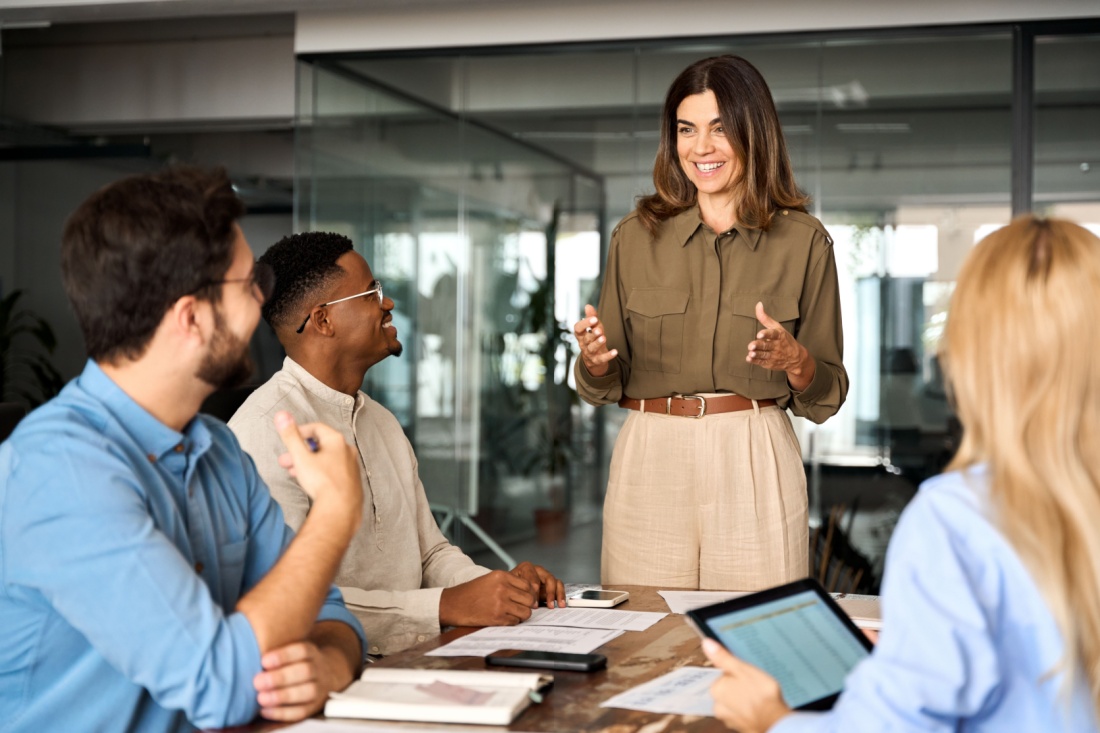 A woman speaks to a table of people.