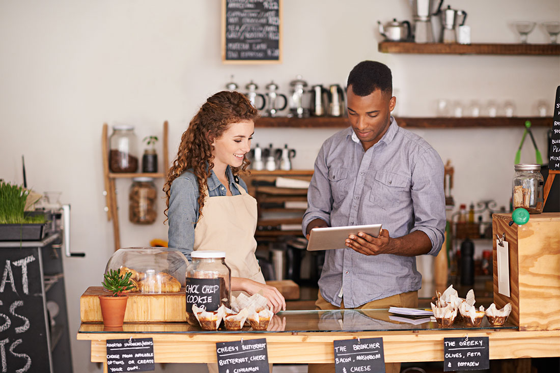 Man and woman at restaurant or small business discussing and looking at tablet