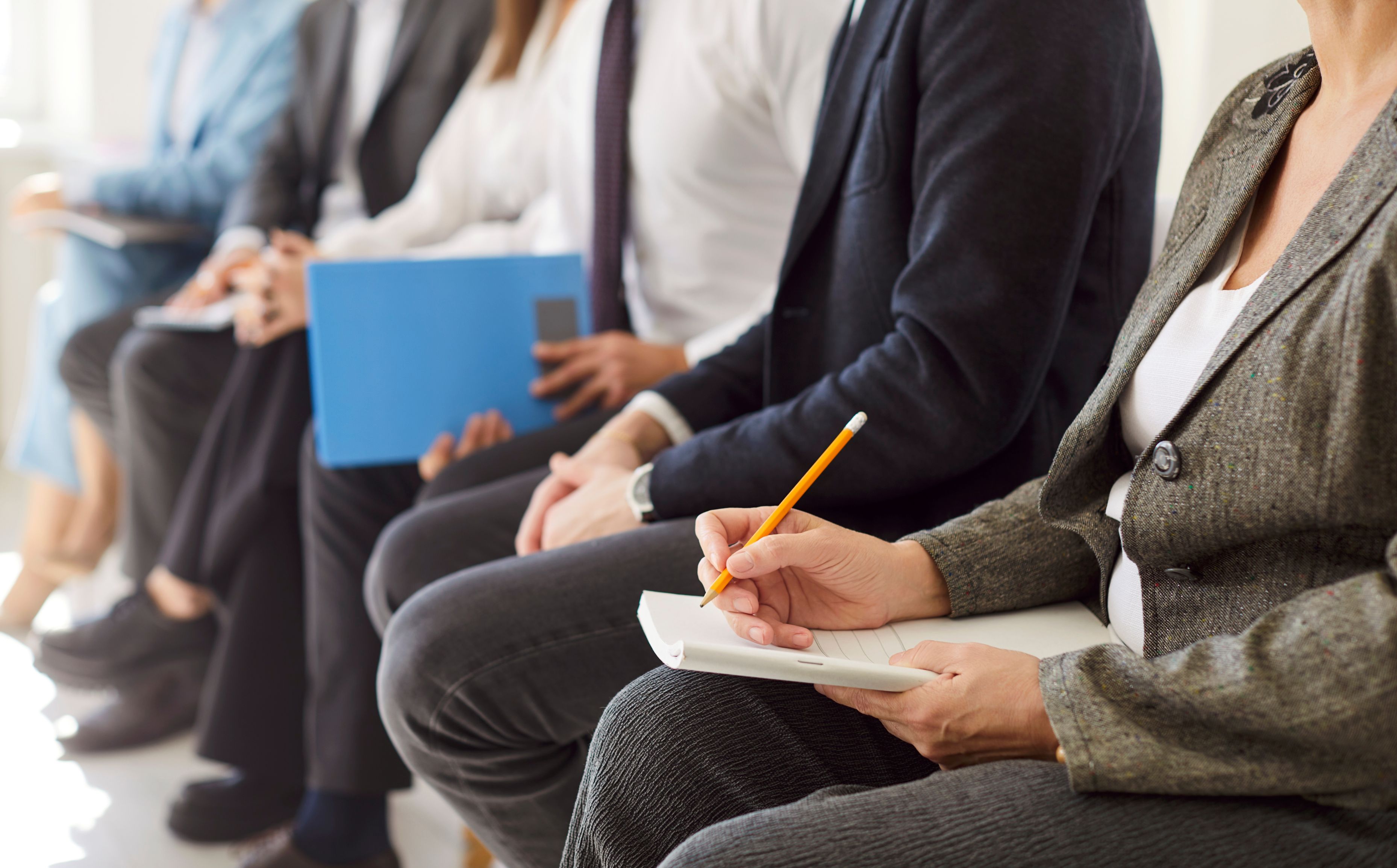 Professionals in business attire sit in a row taking notes during a coaching session