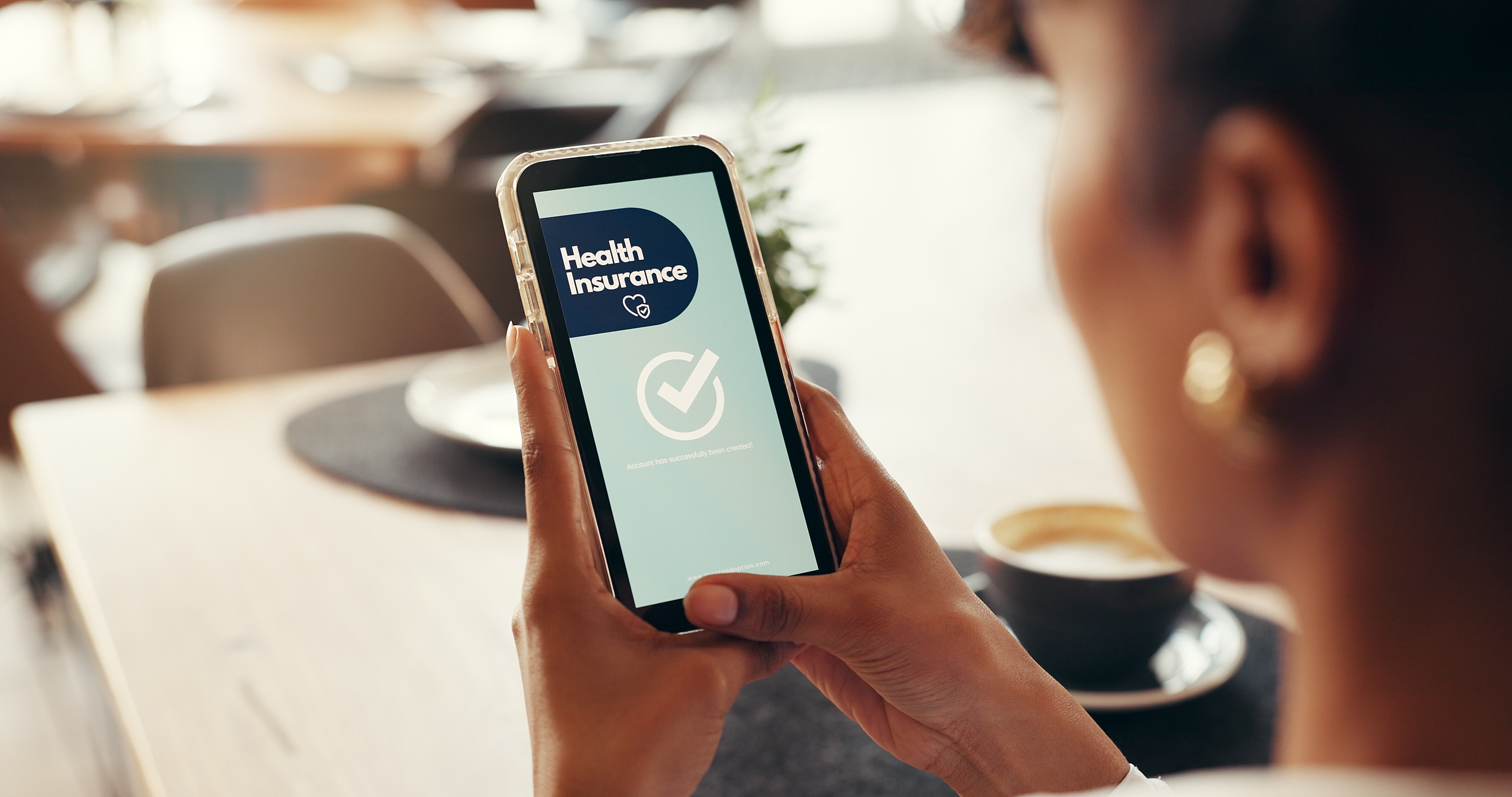 Person holding smartphone displaying health insurance app with checkmark confirmation screen