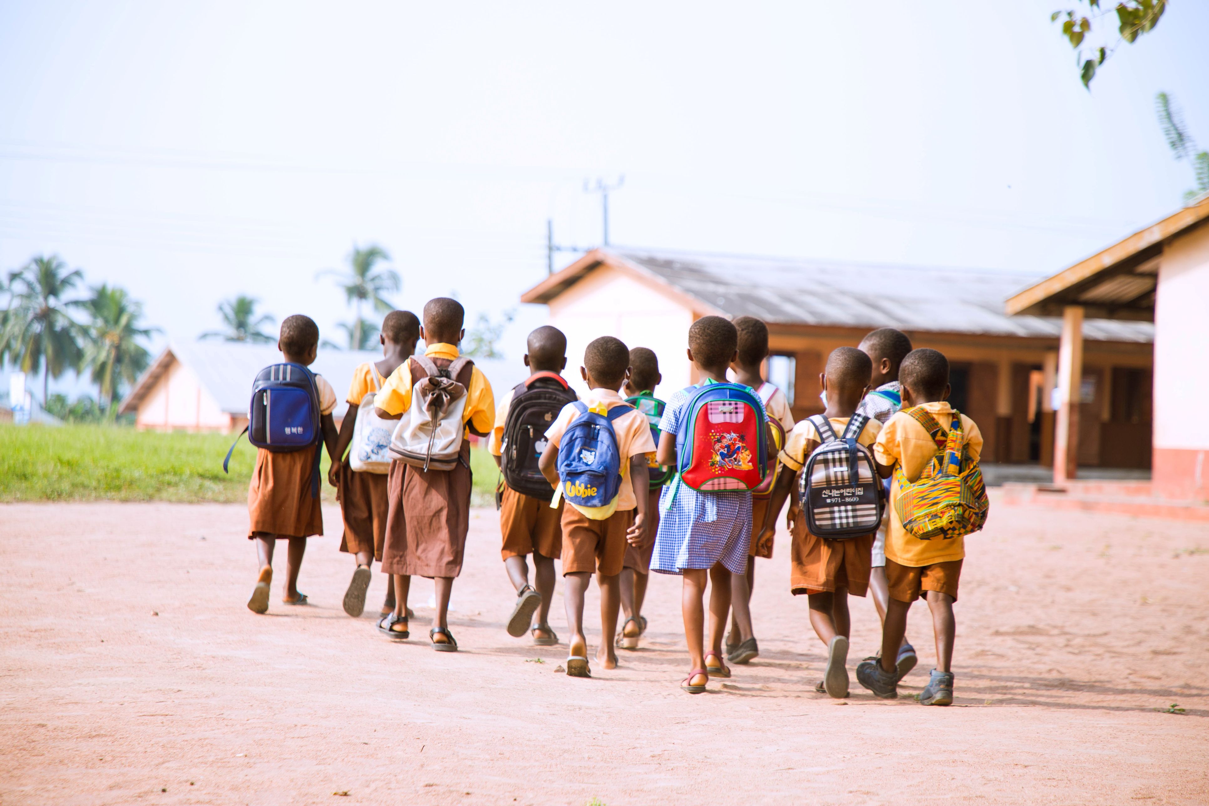 Students with backpacks walking toward school building in rural community