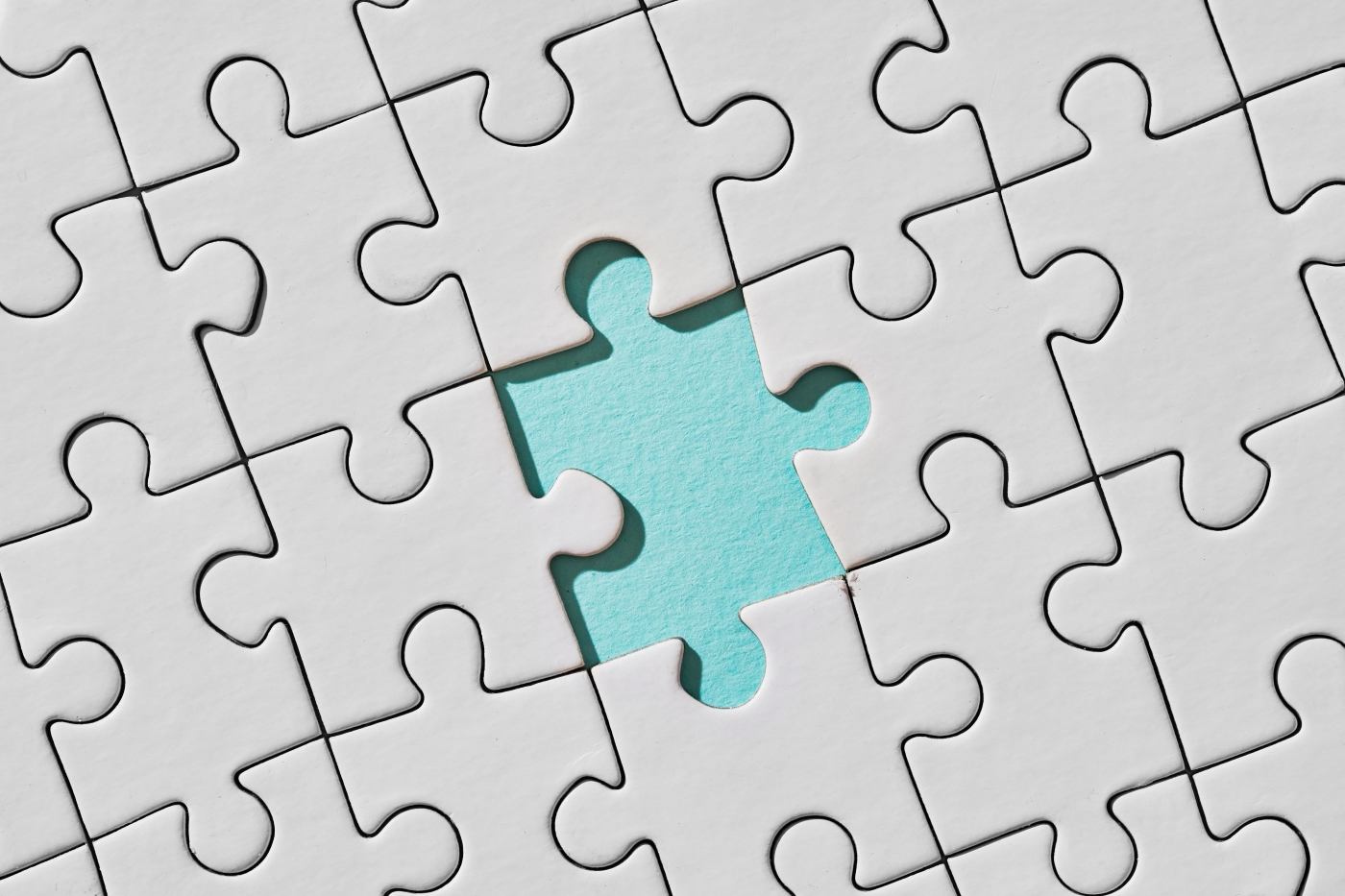 White puzzle with one turquoise piece missing, revealing the gap beneath