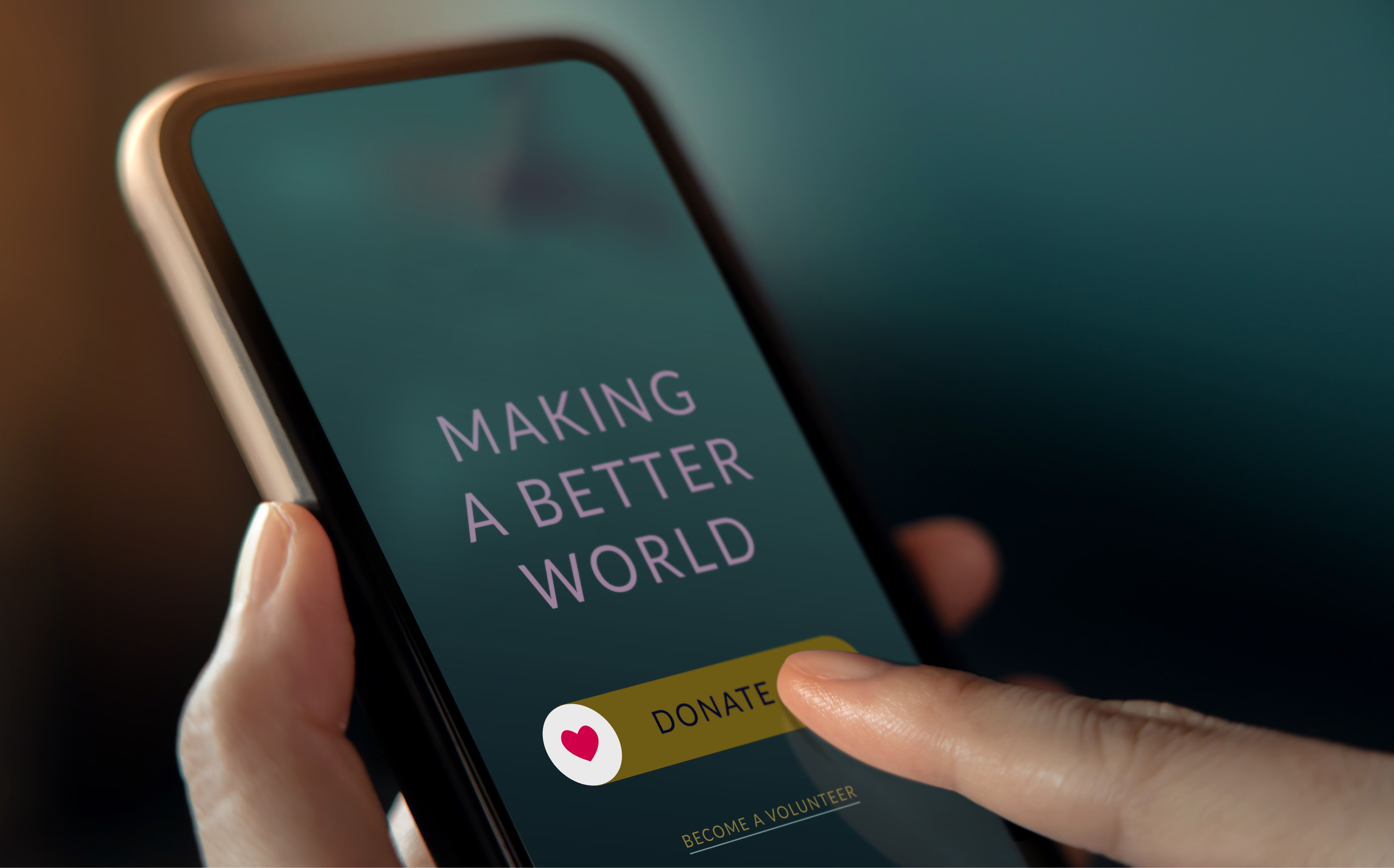 Person's finger hovering over donate button on smartphone displaying making a better world message