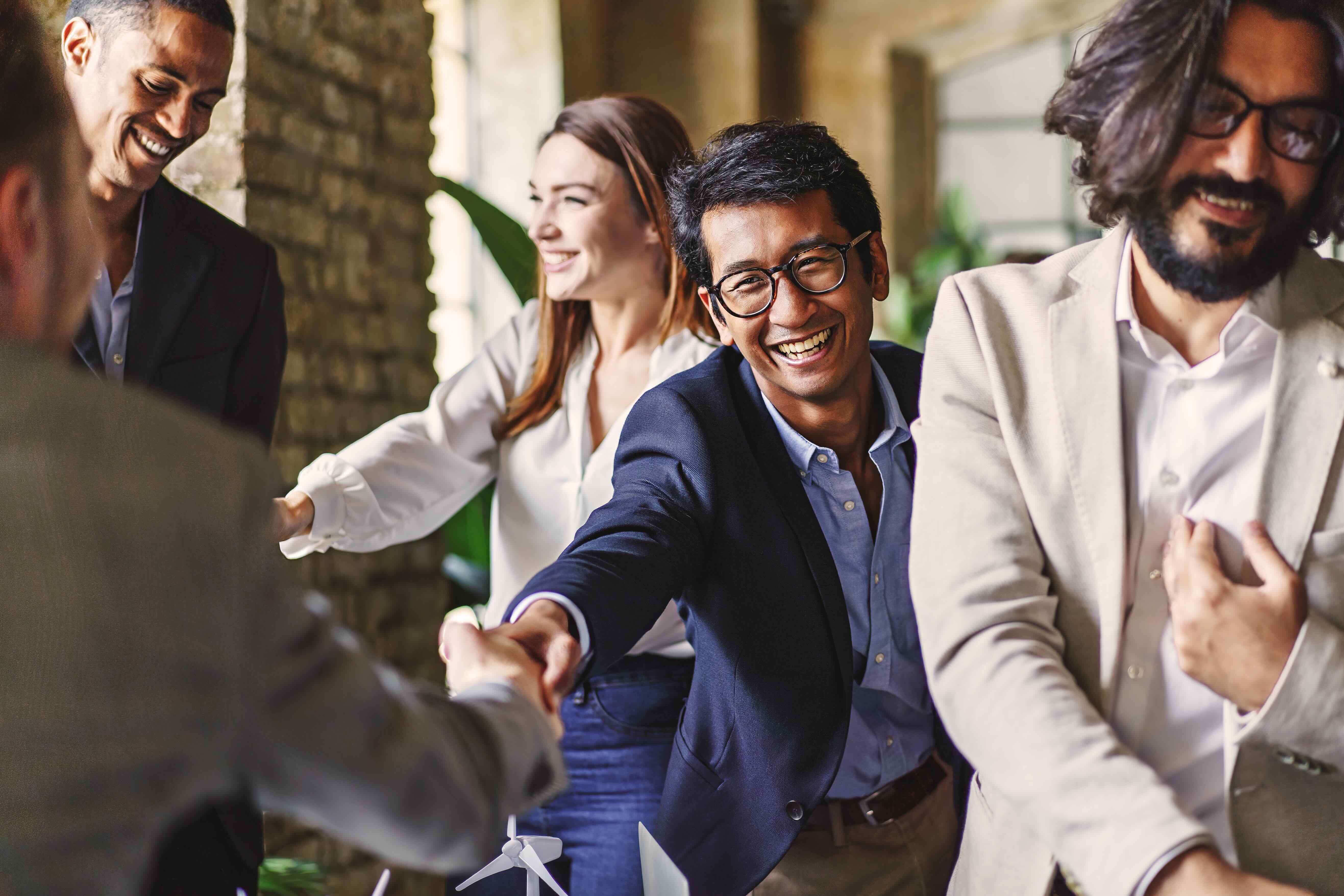 Diverse business professionals smiling and shaking hands at a networking event
