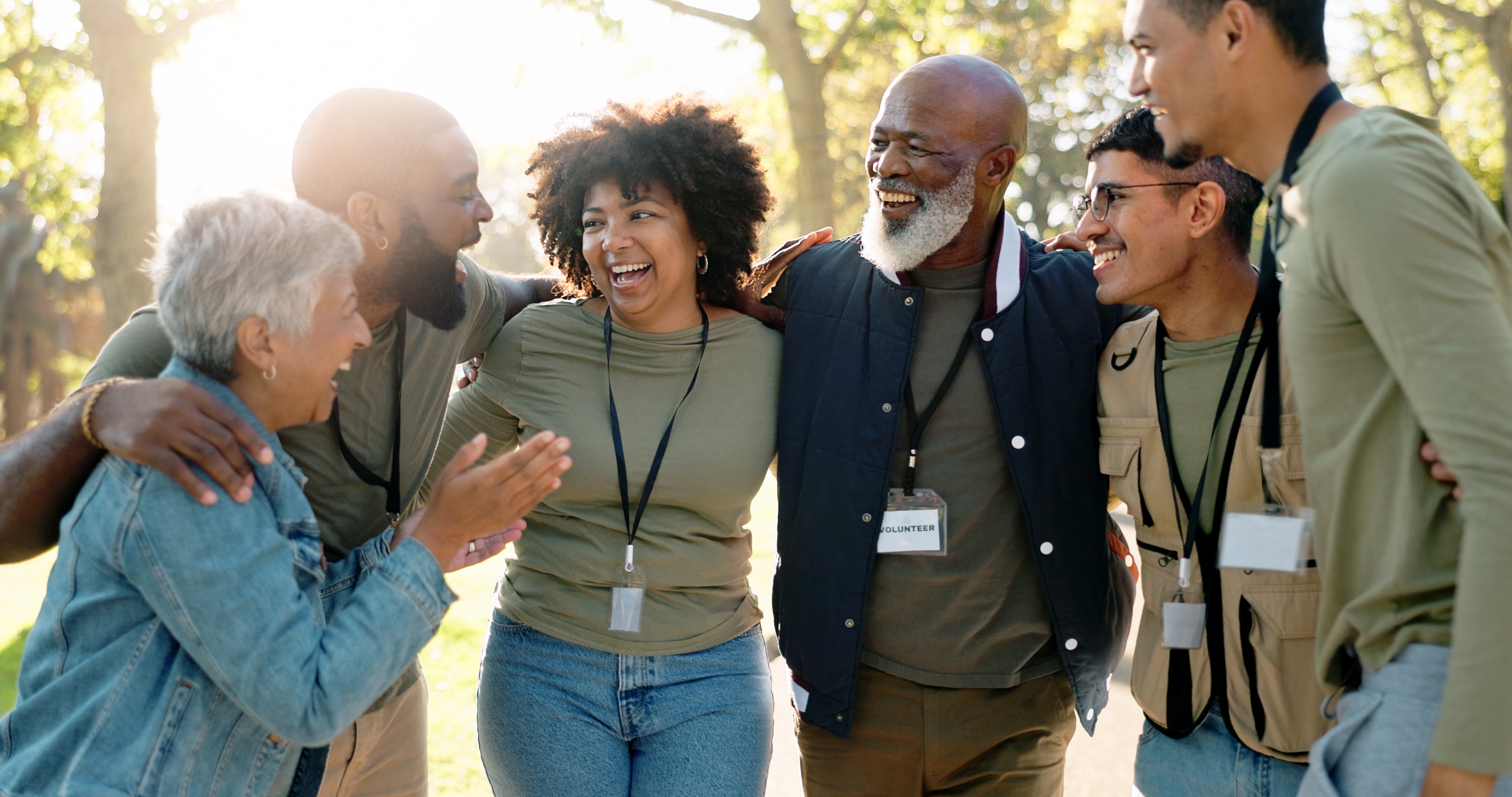 Group of volunteers laughing together outdoors while wearing name badges