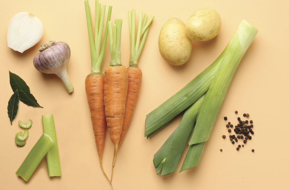 Fresh vegetables and ingredients for sustainable cooking including carrots, potatoes, leeks, garlic, and celery