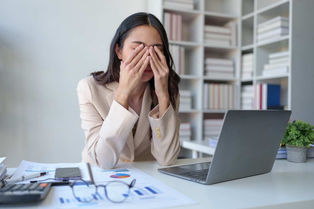 a woman looking stressed while sitting at her work desk