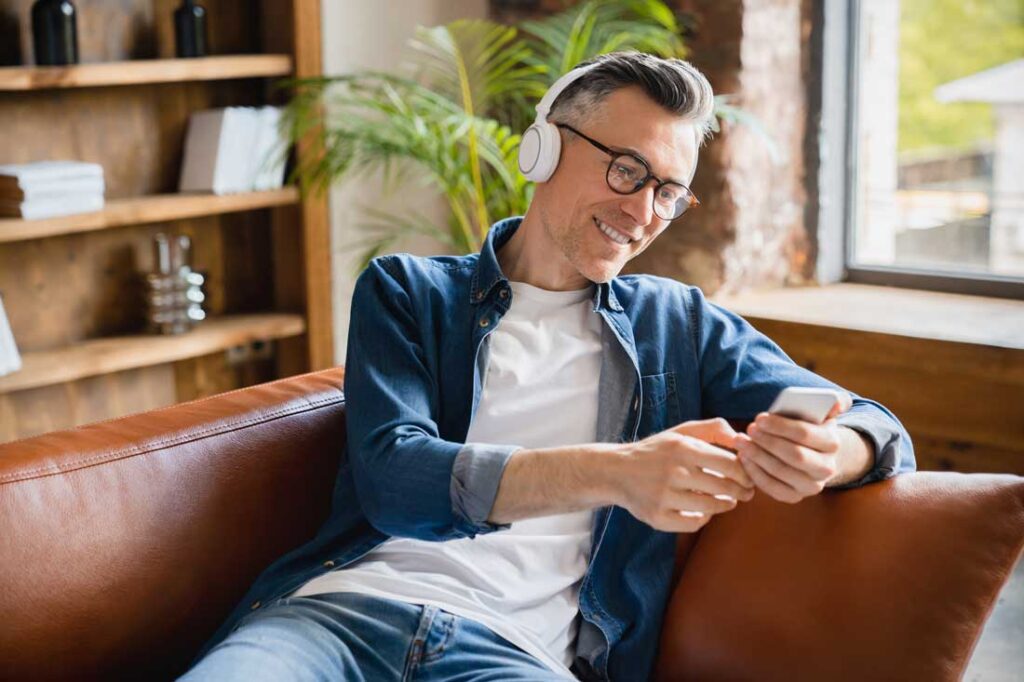 older entrepreneur using headphones to listen to a podcast