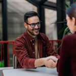 Smiling businessman looking at the female colleague, shaking hands