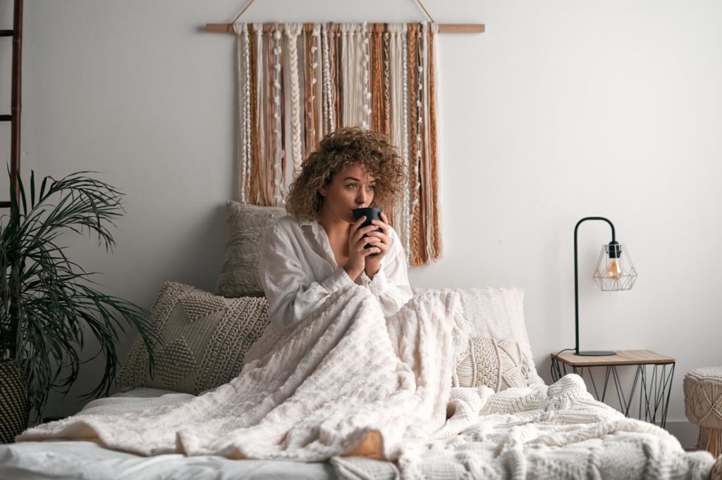 woman starts her day drinking coffee in bed