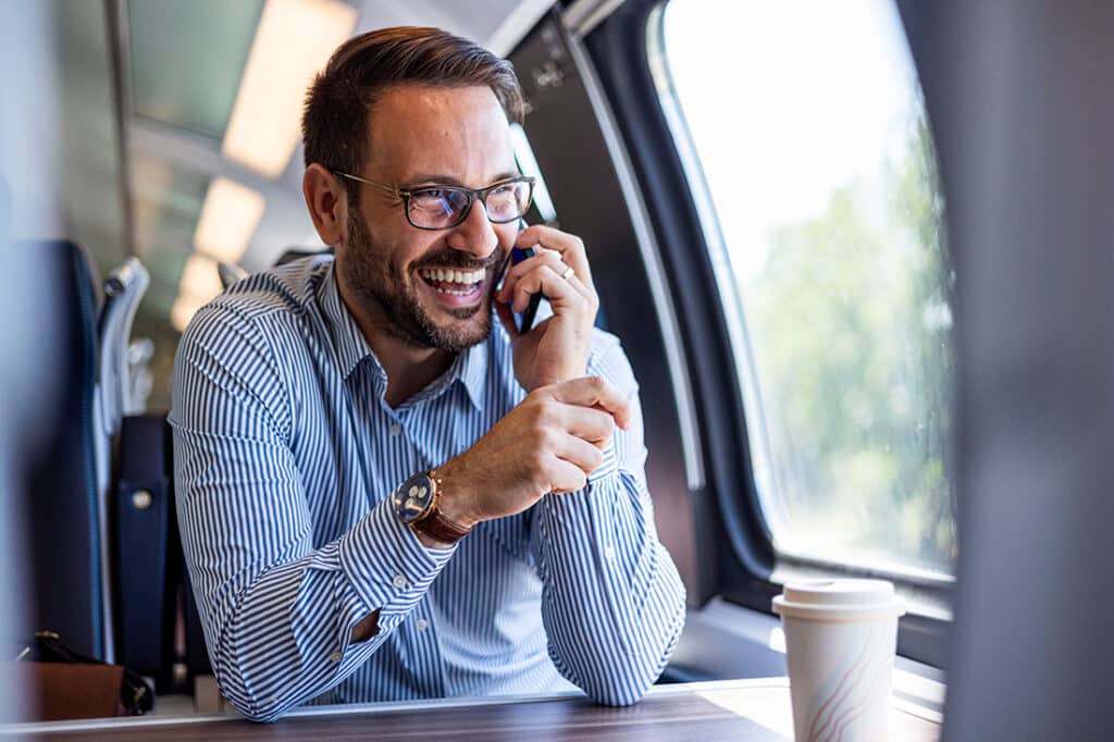 A happy man takes a work call from a train