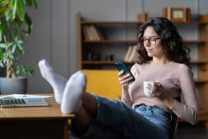 woman succumbing to procrastination by looking at phone