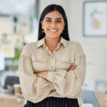 a woman standing with her arms crossed smiling at the camera