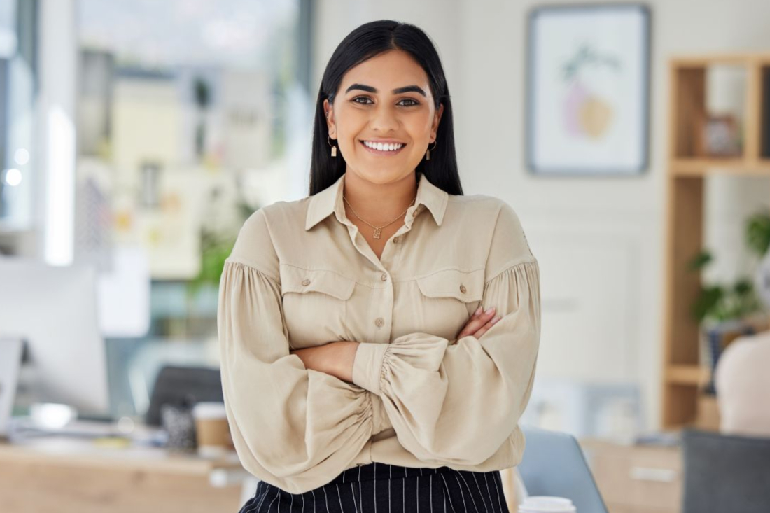 a woman standing with her arms crossed smiling at the camera