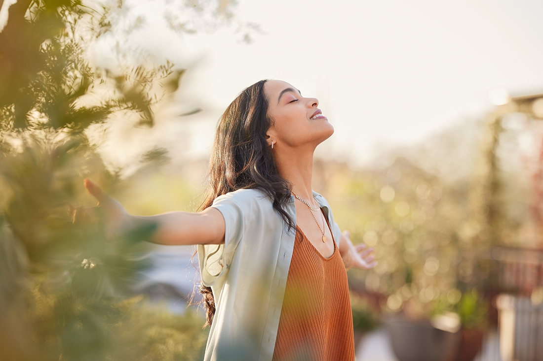 A happy woman stands outside in nature