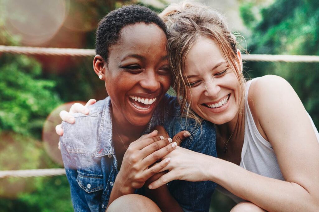 Two women embracing and laughing while reading gratitude quotes