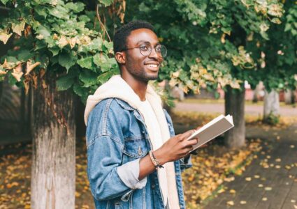 happy millennial man reading book outside