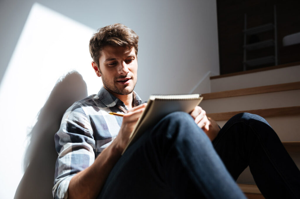 man writing down negative thoughts to embrace positivity for health