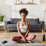 woman in activewear practicing yoga on a mat in a cozy living room setting