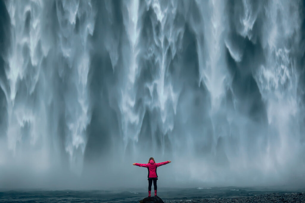 women stands in a waterfall inspired by bravery quotes