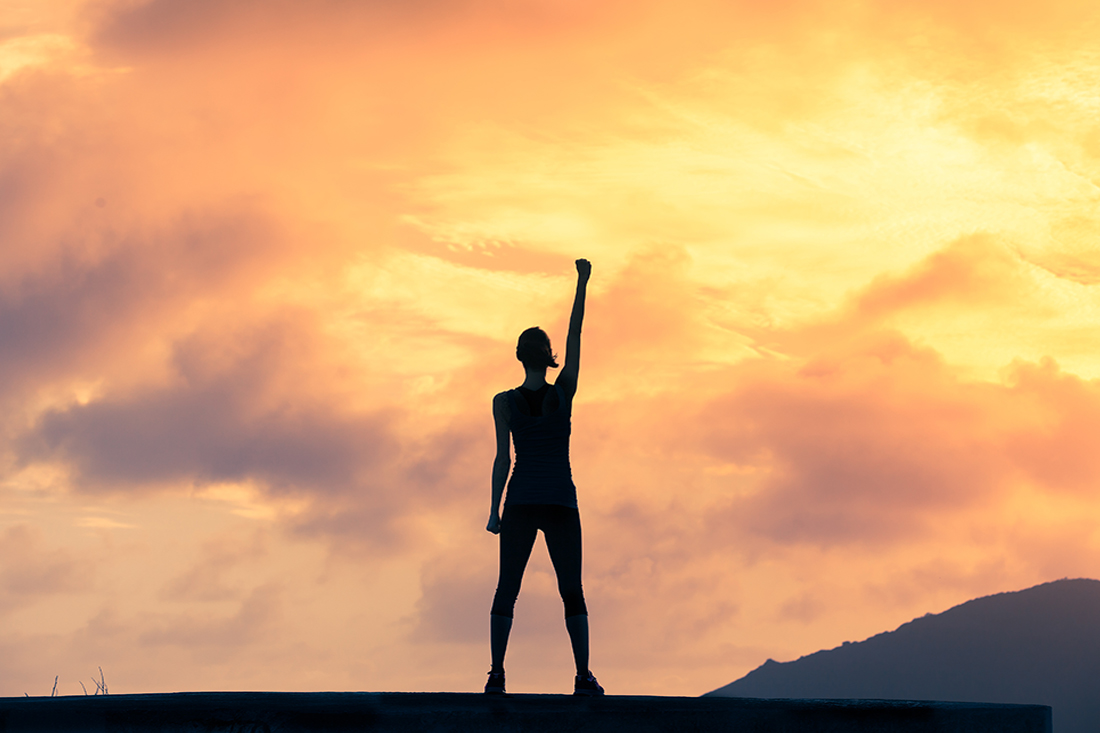 Stand strong. Woman with fist in the air. Feeling motivated, strength and courage concept.