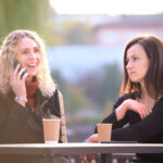 Two women sitting together, one is on the phone and the other is realizing it's time to end the friendship