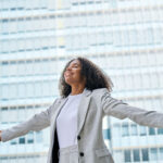 Confident professional young African American business woman wearing suit outstretching arms