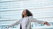 Confident professional young African American business woman wearing suit outstretching arms
