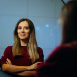 A confident woman smiles at her reflection in a mirror