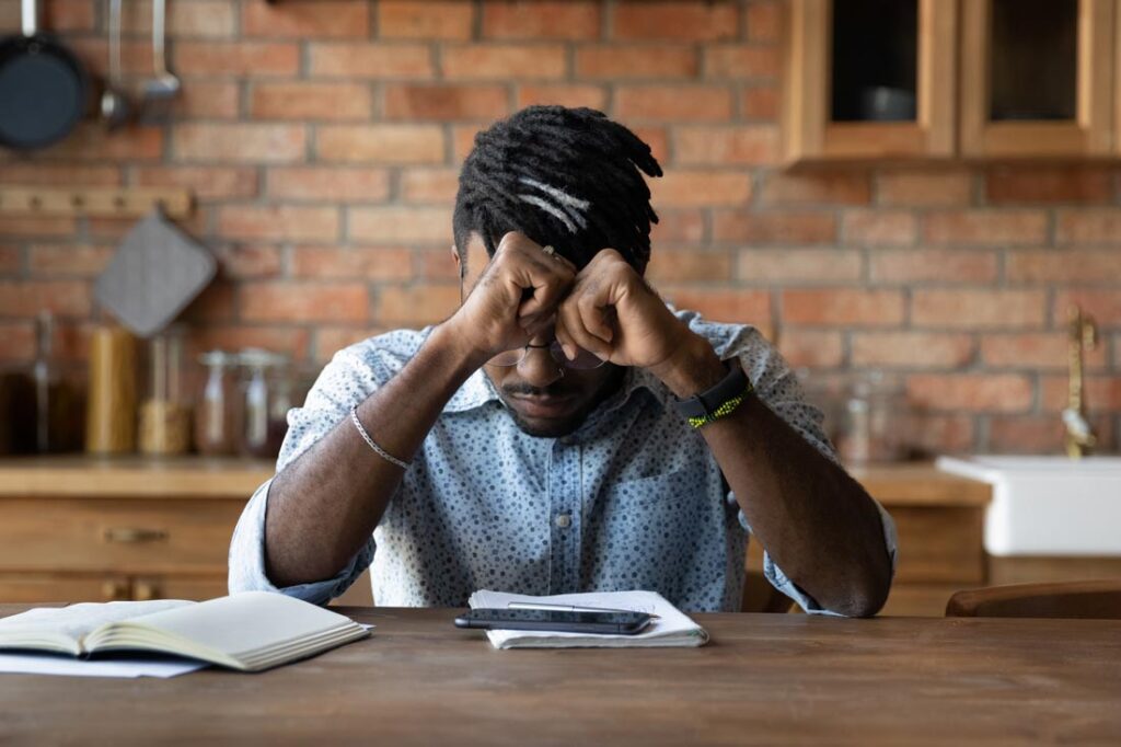 man sitting at a table with head in his hands dwelling on negative mental filters