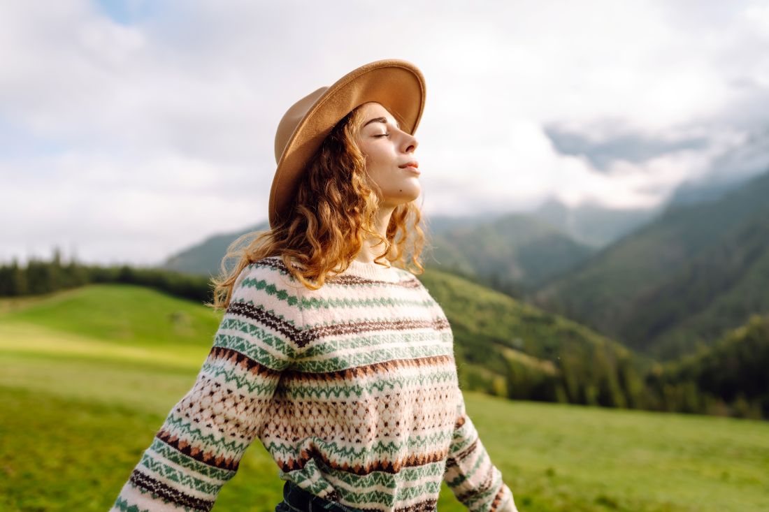 a woman standing in a field looking up to the sky while her eyes are closed