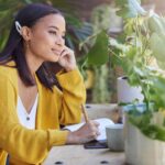 Woman writing in her journal surrounded by plants visualizing the future