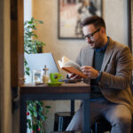 Businessman Reading Book while Sitting in Cafe