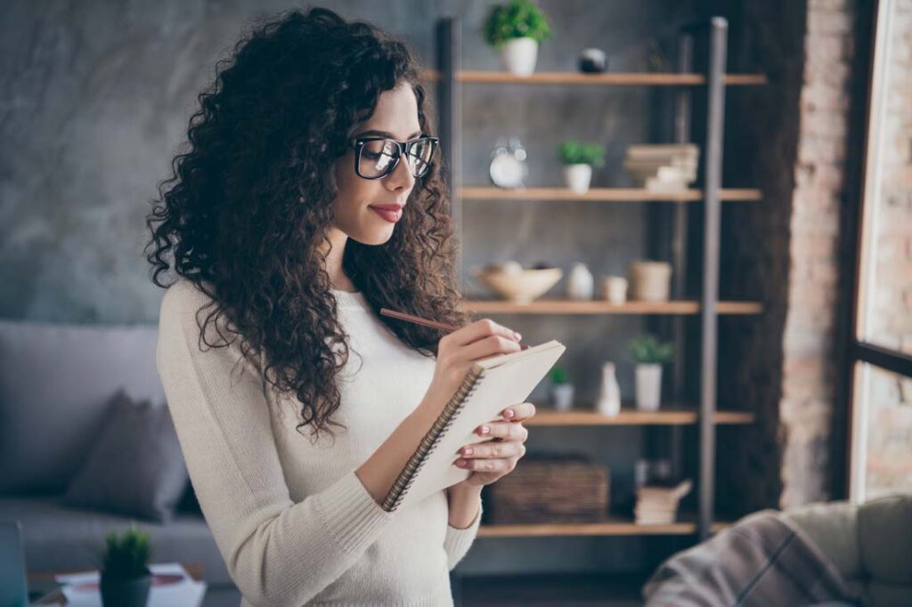 woman writes to-do list as a way to be organized and productive