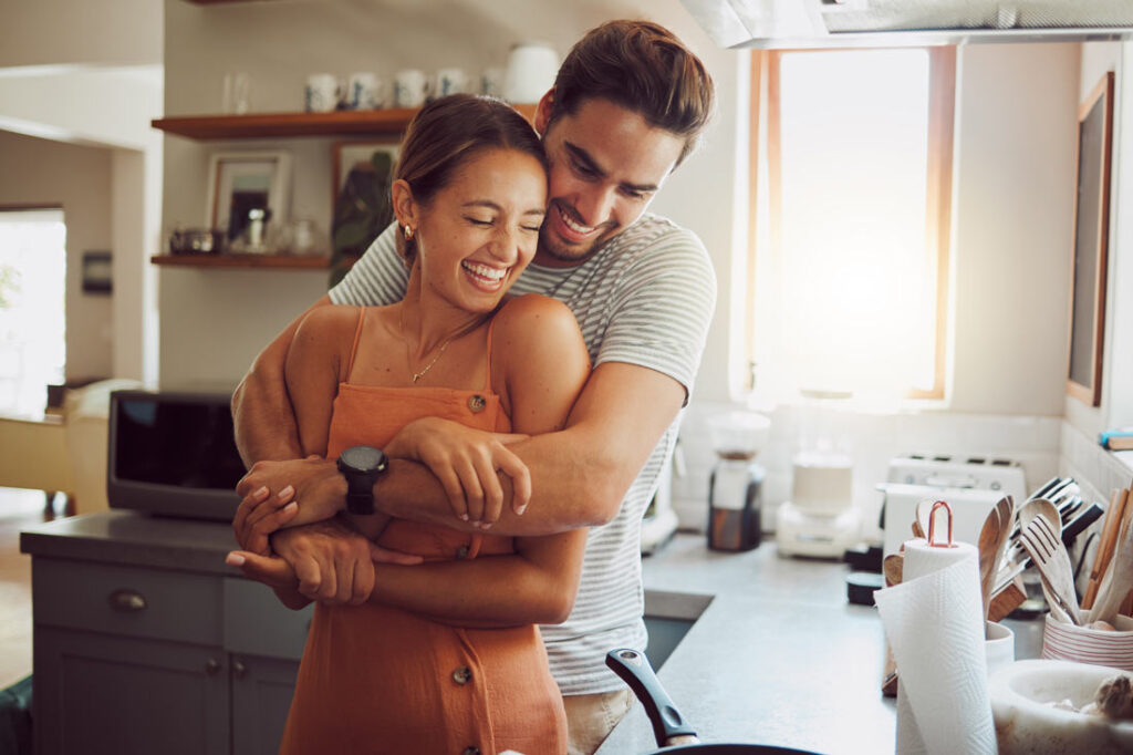 Happy couple hugging in their kitchen because they understand the importance of enneagram relationships