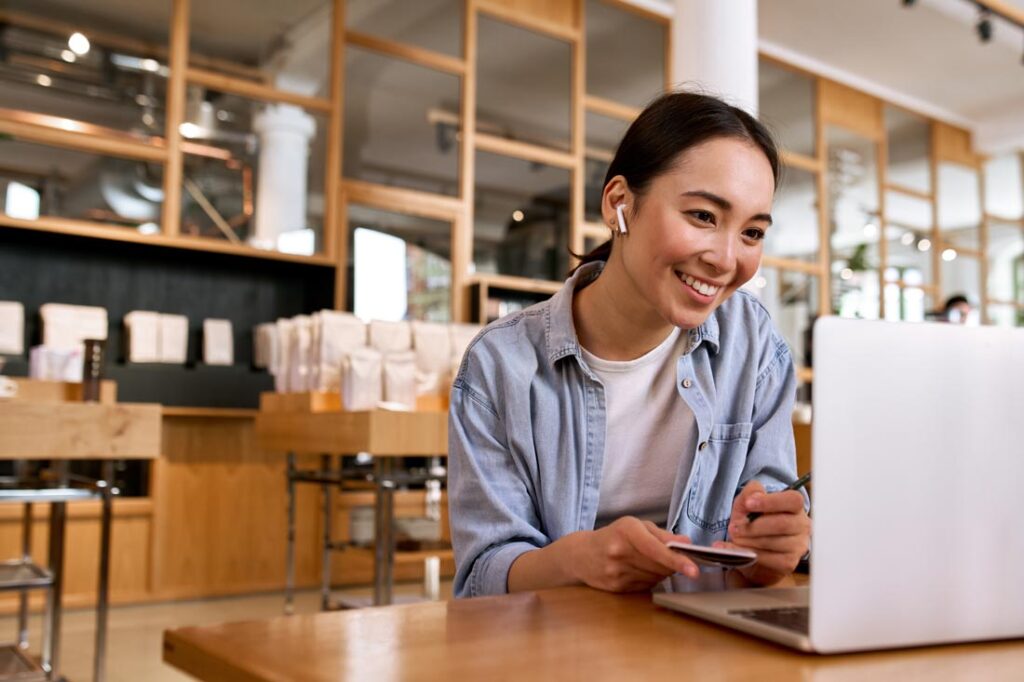 Asian woman working at a cafe on her computer showing her remote leadership skills