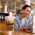 Asian woman working at a cafe on her computer showing her remote leadership skills