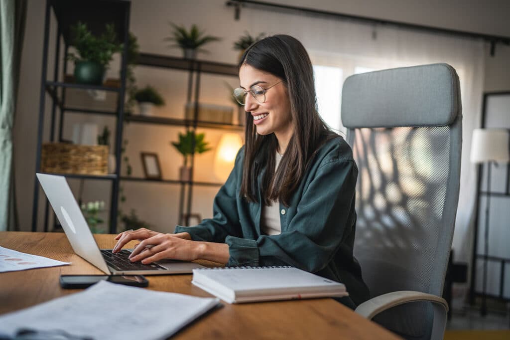 Adult woman work on laptop and use notebook from home office