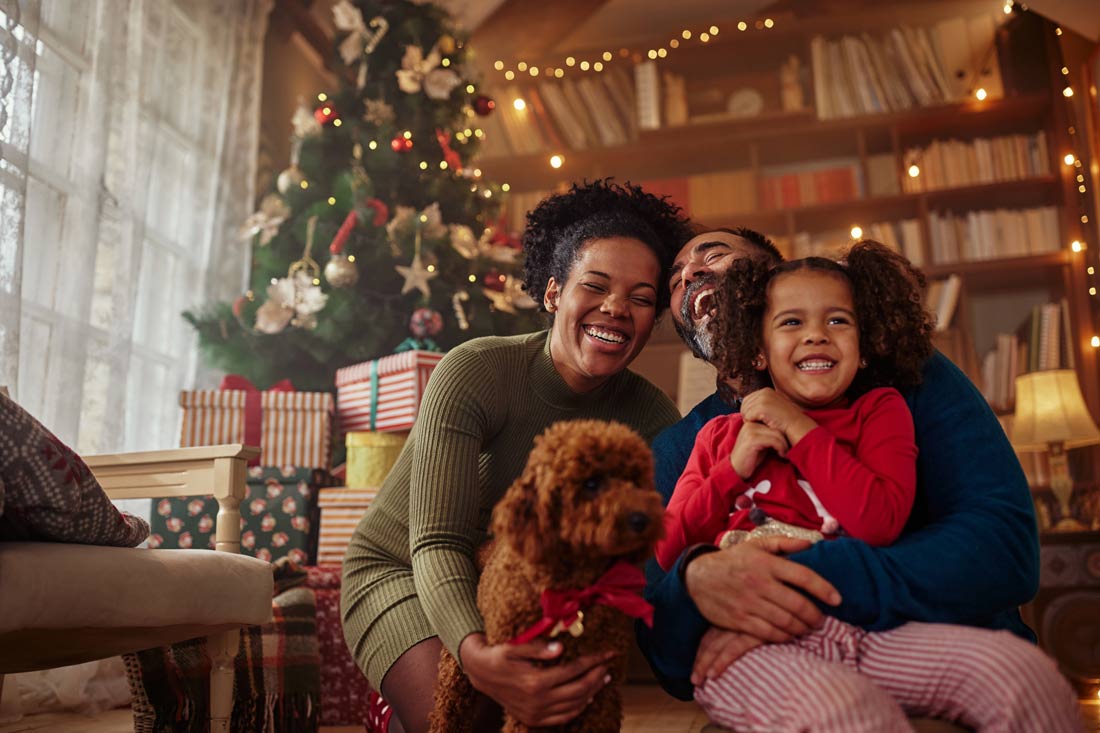 Happy family in front of their Christmas tree reading quotes about Christmas