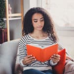 Woman sitting in armchair reading a book