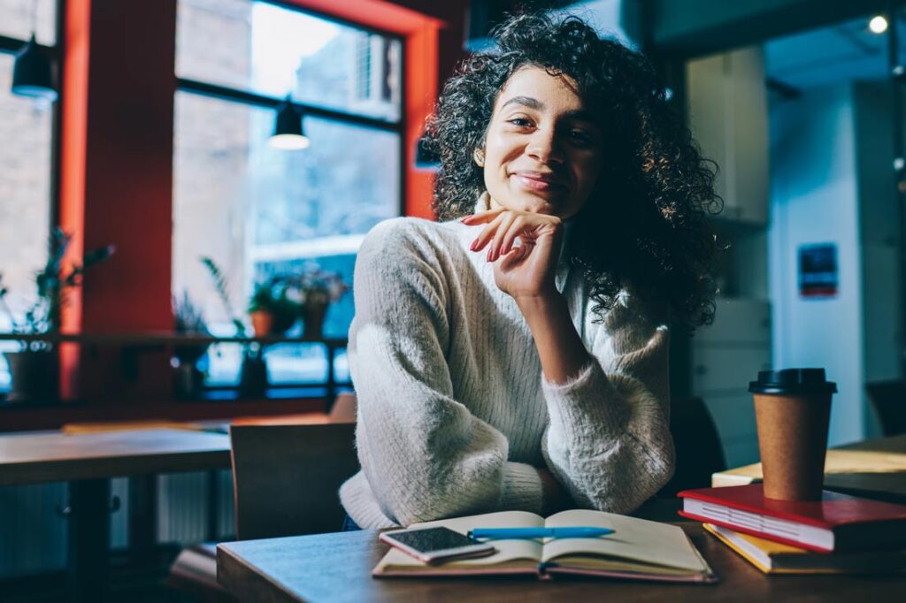 Woman smiling at a cafe learning about goal setting theory