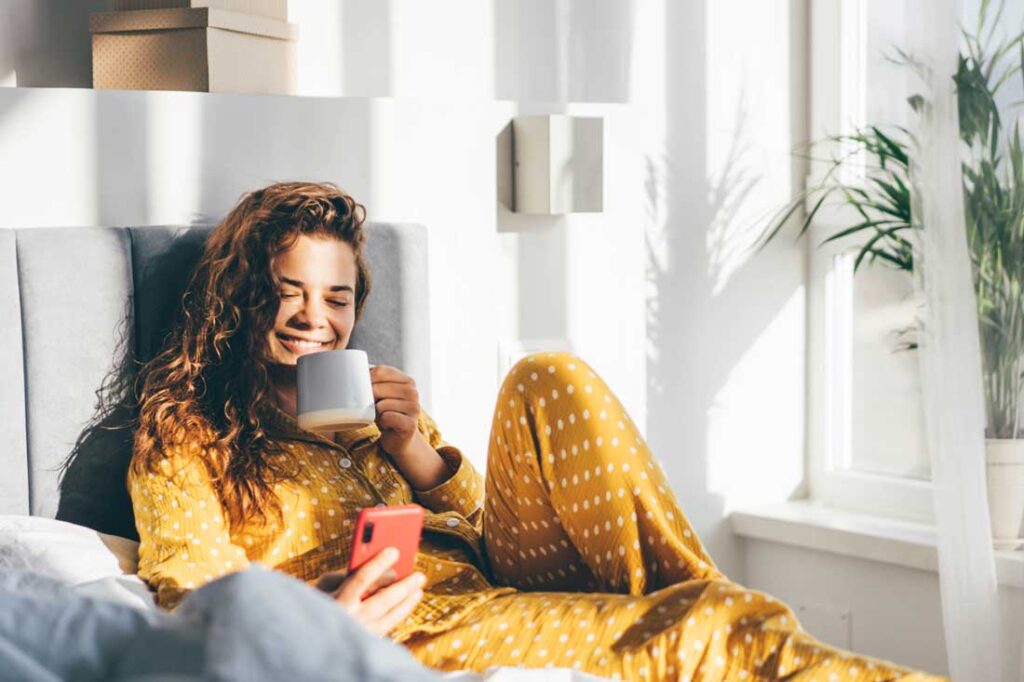 woman in bed drinking coffee after daylight saving time