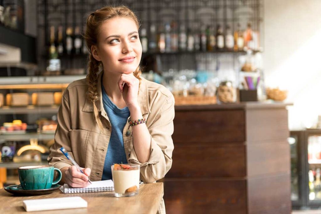 young woman journaling in cafe