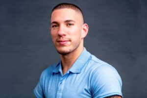 Photograph of Nick Santonastasso, a young handsome bald man with amelia in a light blue collared shirt, on gaining self awareness