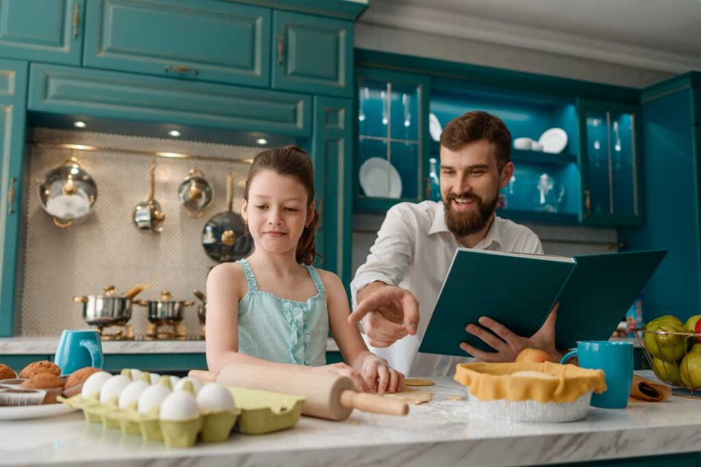 father and daughter making recipe from a health cookbook