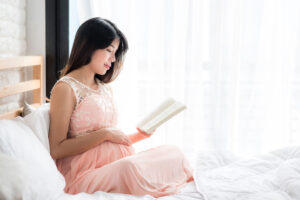 expecting mom reading book in bed